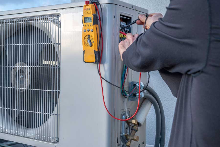 Technician using tools to test and repair an outdoor AC unit